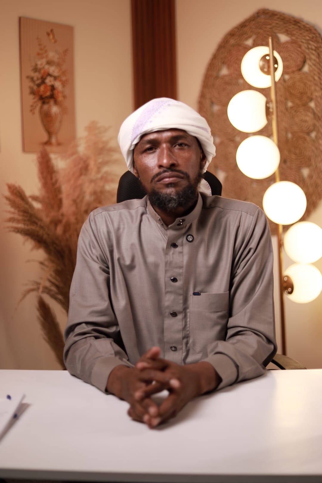 الشيخ أحمد عبد الله سعيد جالسًا في غرفة دافئة الإضاءة